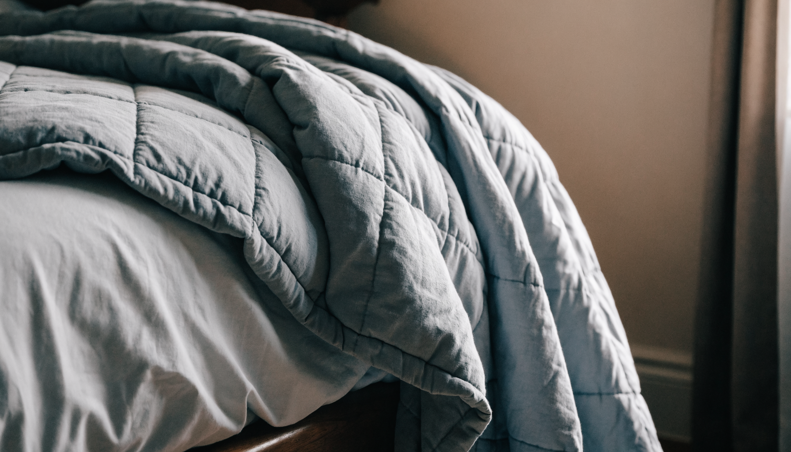 Couverture lestée grise repliée sur le coin d'un lit Image