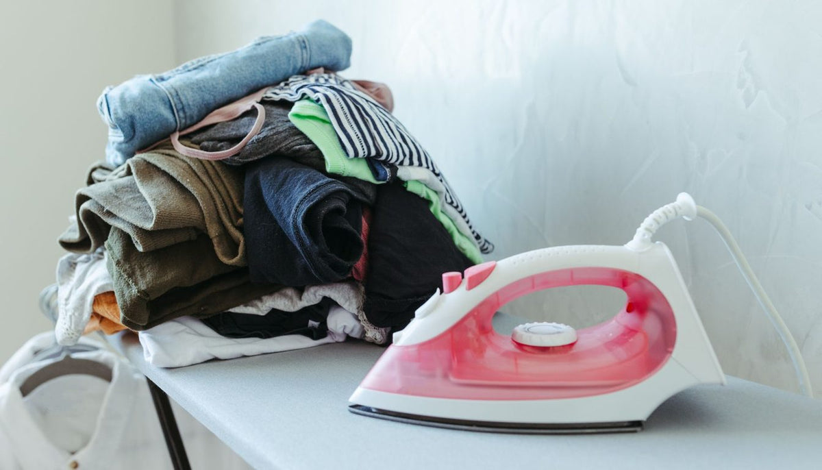 Fer à repasser posé près d'une pile de linge plié sur une table à repasser Image
