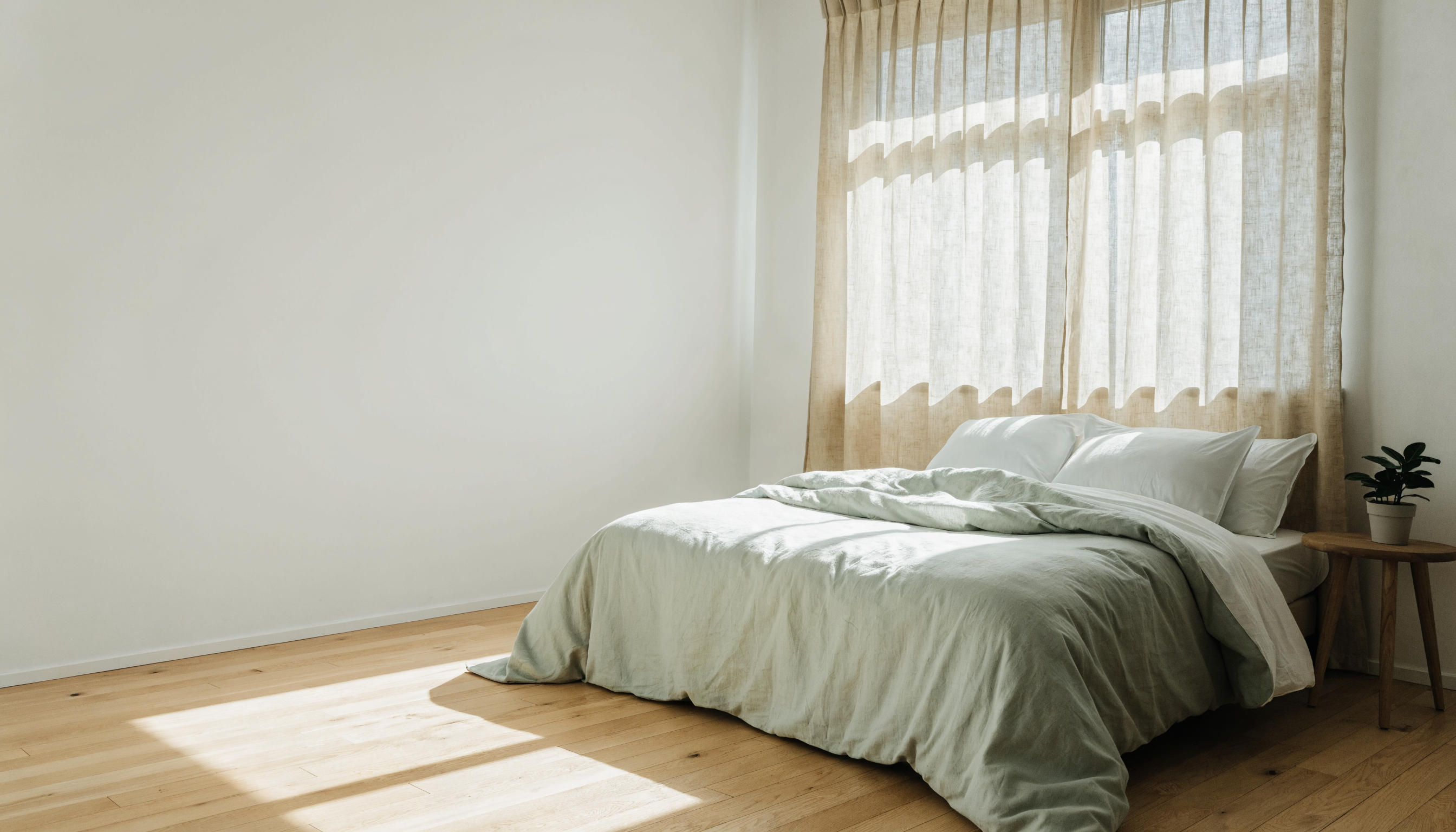 Lit habillé d'une housse de couette blanche et vert sauge dans une chambre claire